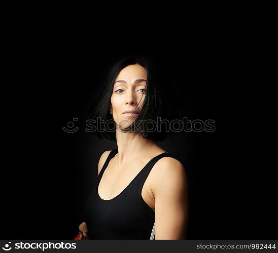 portrait of a beautiful young woman with black hair on a dark background, emotional impulse