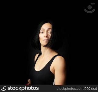portrait of a beautiful young woman with black hair on a dark background, emotional impulse