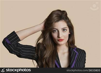 Portrait of a beautiful young woman with hand in hair over colored background