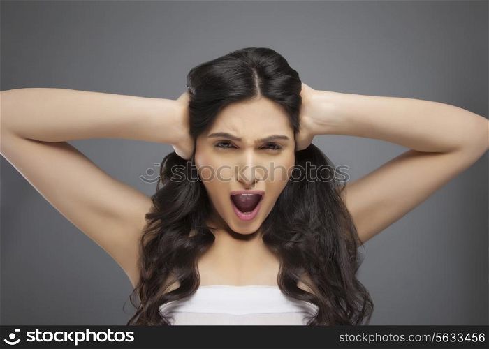 Portrait of a beautiful young woman with hands over ears against colored background