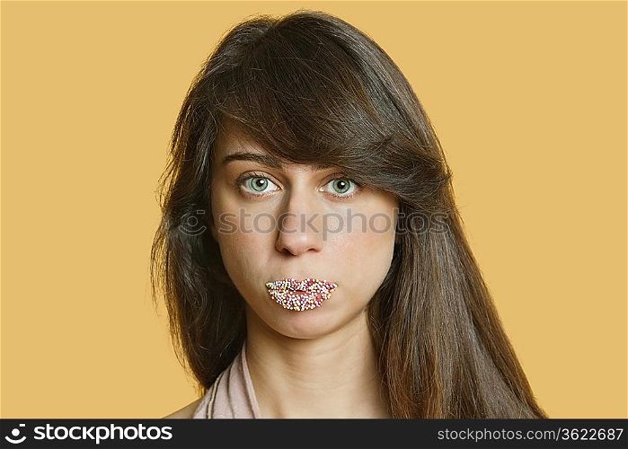 Portrait of a beautiful young woman with sprinkled lips over colored background