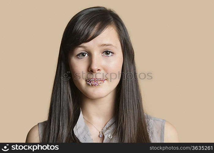 Portrait of a beautiful young woman with sprinkled lips over colored background