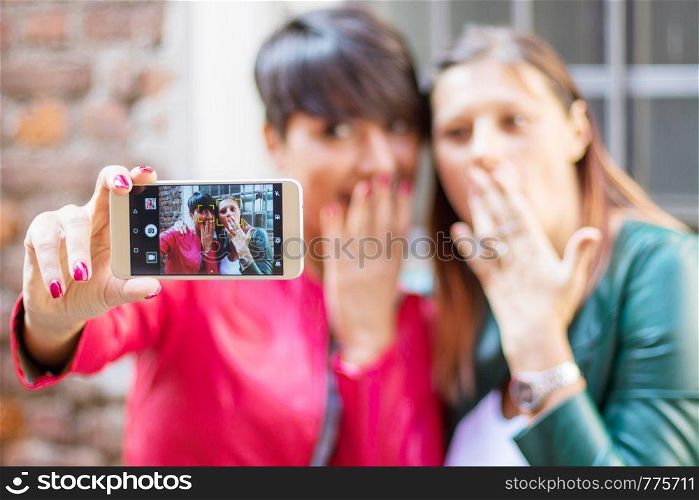 Portrait of a beautiful young women doing selfie in the city with a smartphone