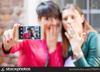 Portrait of a beautiful young women doing selfie in the city with a smartphone