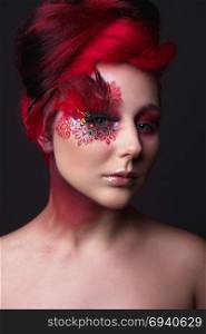 Portrait of a beauty young girl with red hair. Creative ingenious makeup with feathers, rhinestones and large eyelashes. Young girl with red hair and creative ingenious makeup