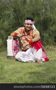 Portrait of a Bihu dancer sitting with a dhol
