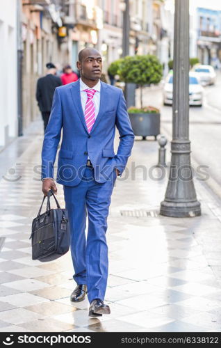 Portrait of a black business man walking on the street with a modern briefcase