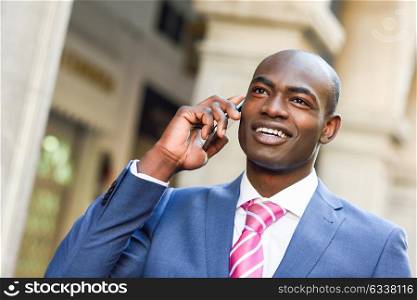 Portrait of a black businessman wearing suit talking with his smartphone in urban background