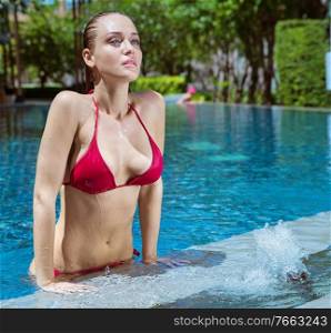 Portrait of a blond, beautiful woman in a tropical swimming - pool