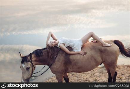Portrait of a blond beautiful woman lying on the horse