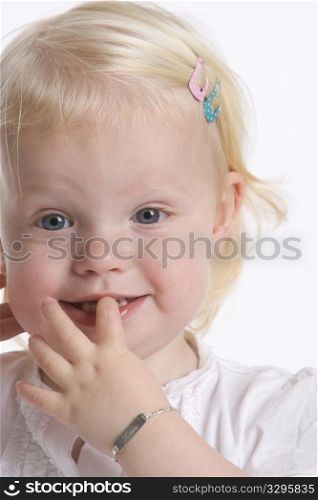 Portrait Of A Blond Toddler Girl With A Finger In Her Mouth