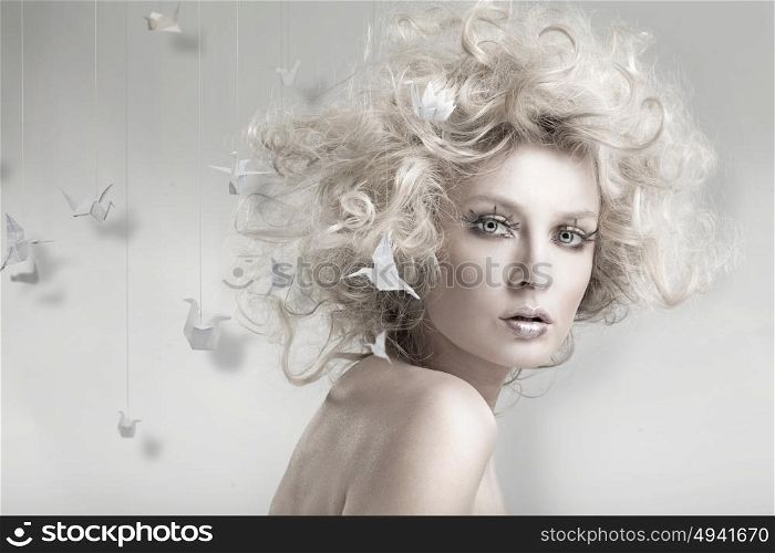Portrait of a blond woman among origami swans