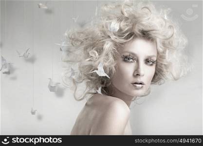 Portrait of a blond woman among origami swans