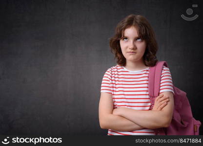 Portrait of a bored schoolgirl holding backpack, looking at camera. Bored schoolgirl holding backpack, looking at camera