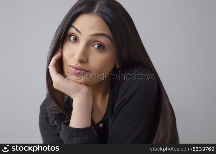 Portrait of a bored young woman with hand on chin isolated over colored background