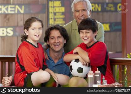 Portrait of a boy and a girl with their father and grandfather sitting in a restaurant and smiling
