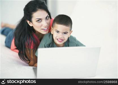 Portrait of a boy and his mother smiling in front of a laptop
