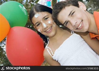 Portrait of a boy and his sister wearing birthday hats and smiling