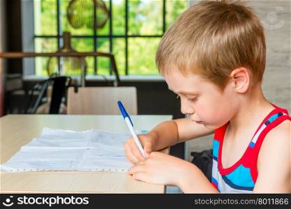 Portrait of a boy at the table drawing a pictures