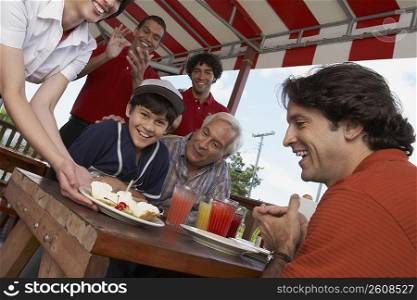 Portrait of a boy celebrating his birthday with his father and grandfather in a restaurant