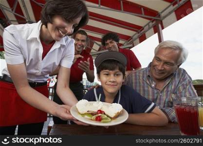 Portrait of a boy celebrating his birthday with his grandfather in a restaurant