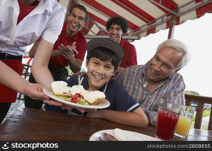 Portrait of a boy celebrating his birthday with his grandfather in a restaurant