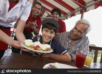 Portrait of a boy celebrating his birthday with his grandfather in a restaurant