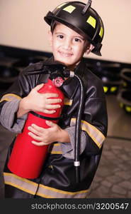 Portrait of a boy dressed as a firefighter and holding a fire extinguisher