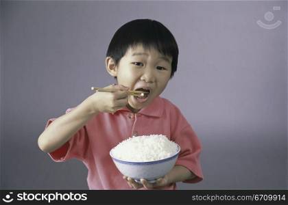 Portrait of a boy eating rice with chopsticks