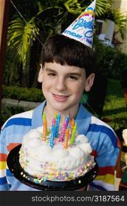 Portrait of a boy holding a birthday cake and smiling