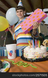 Portrait of a boy holding a birthday present and balloons