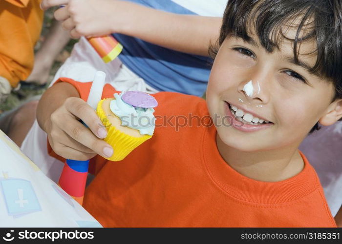 Portrait of a boy holding a cupcake and smiling