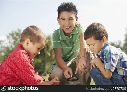 Portrait of a boy holding a magnifying glass with his friends beside him