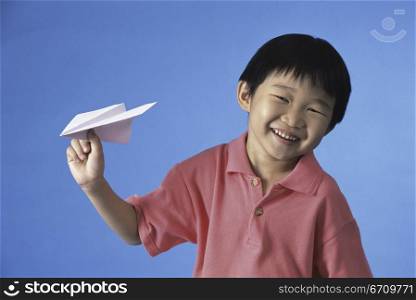Portrait of a boy holding a paper plane smiling