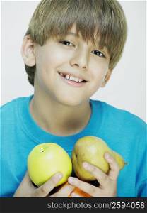 Portrait of a boy holding a pear and an apple