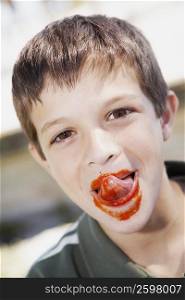 Portrait of a boy licking ketchup from his lips