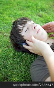 Portrait of a boy listening to music with headphones laid on the grass