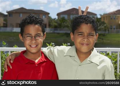 Portrait of a boy making a gesture of rabbit ears behind another boy&acute;s head