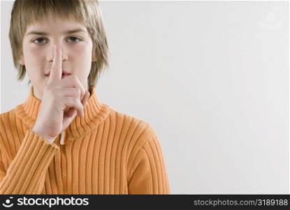 Portrait of a boy showing a silence gesture