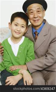 Portrait of a boy sitting on a couch with his grandfather smiling