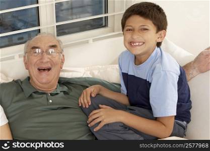 Portrait of a boy sitting with his grandfather on a couch