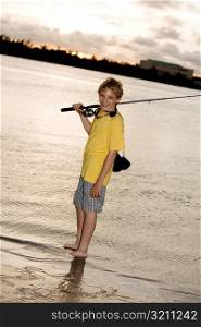 Portrait of a boy smiling carrying a fishing rod