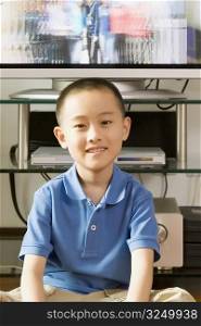 Portrait of a boy smiling in front of a television