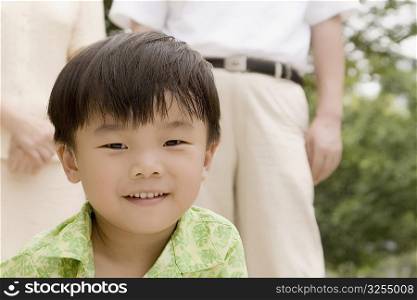 Portrait of a boy smiling with his grandparents standing behind him