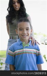 Portrait of a boy smiling with his mother standing behind him