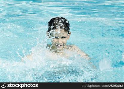 Portrait of a boy splashing water in a swimming pool