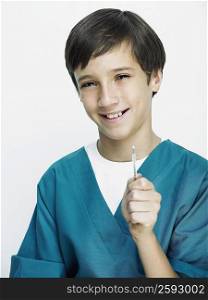 Portrait of a boy wearing surgical scrubs and holding a thermometer