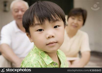 Portrait of a boy with his grandparents sitting behind him