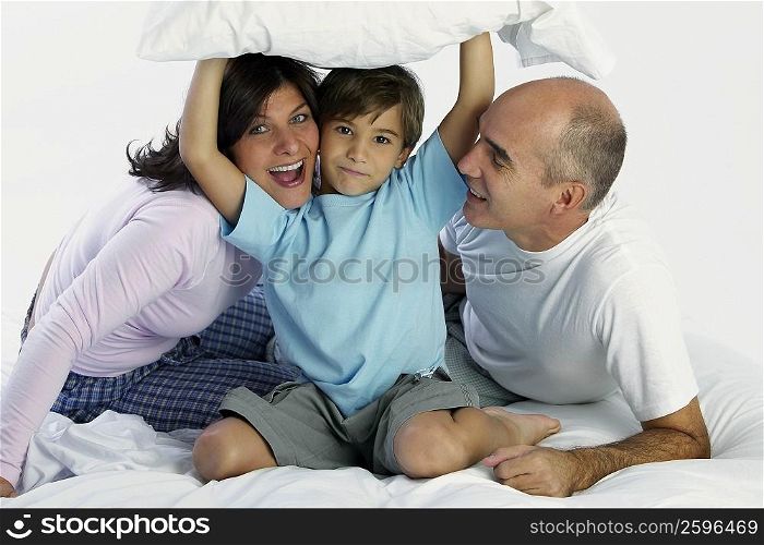Portrait of a boy with his parents on the bed