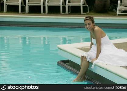 Portrait of a bride sitting at the poolside with her feet in water